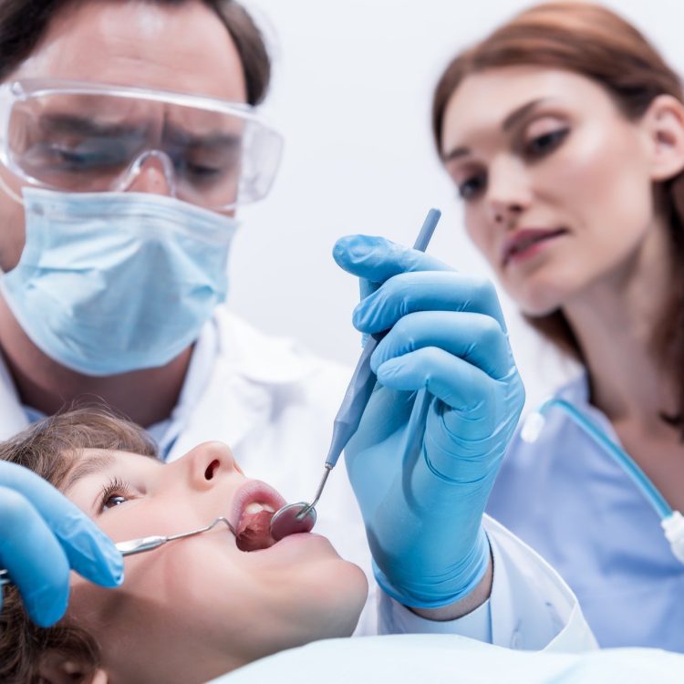 low-angle-view-of-dentists-examining-teeth-of-little-boy-at-dentist-office.jpg